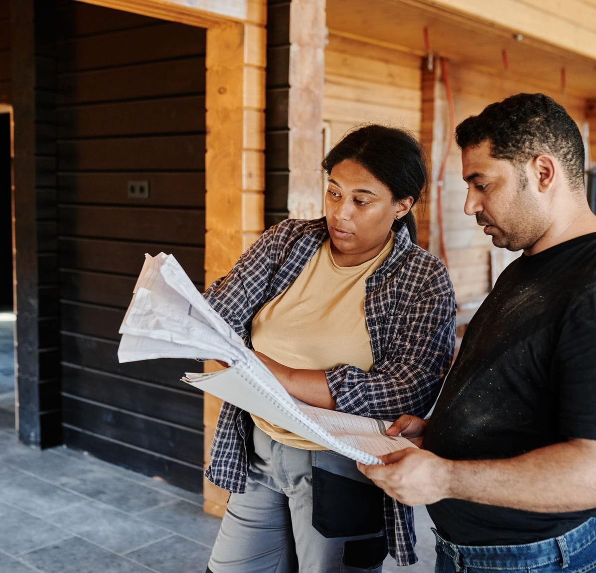 A contractor and a homeowner reviewing renovation plans together on site