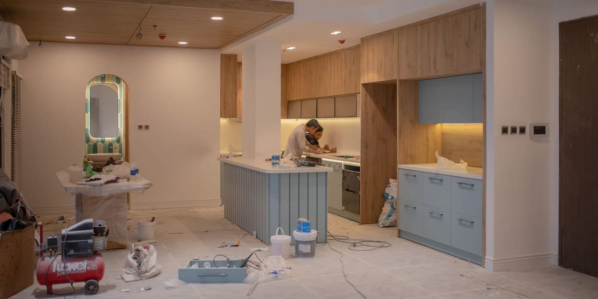 Kitchen remodel in progress with new cabinetry installed and floors protected