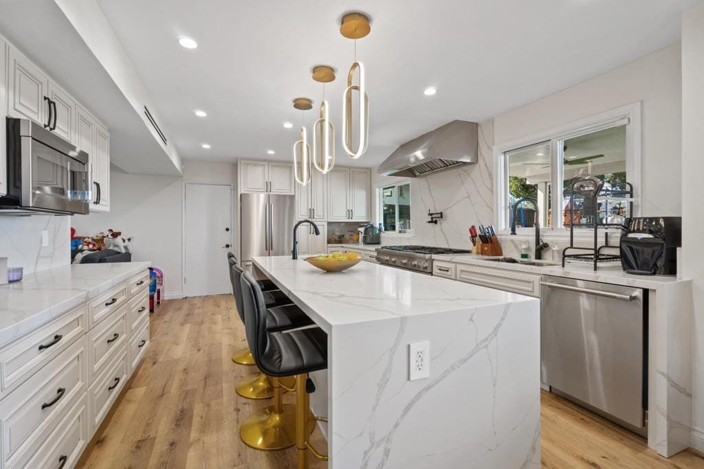 Remodelled kitchen with a white waterfall island, shaker cabinetry and brass pendant lights