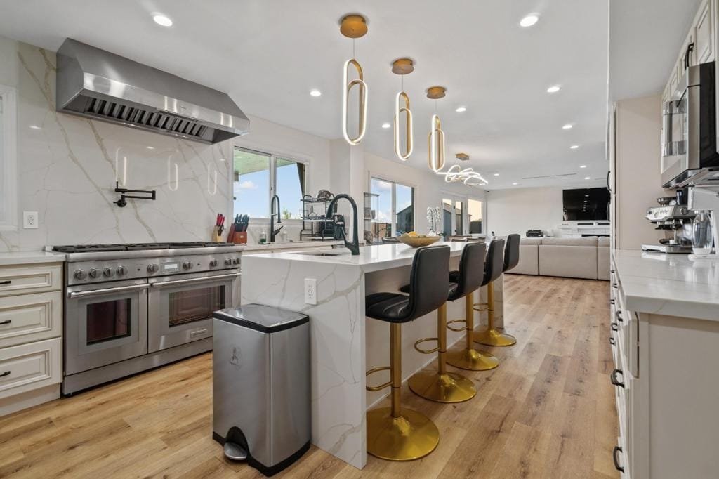 Open kitchen with a professional range, a quartz waterfall island and bar seating