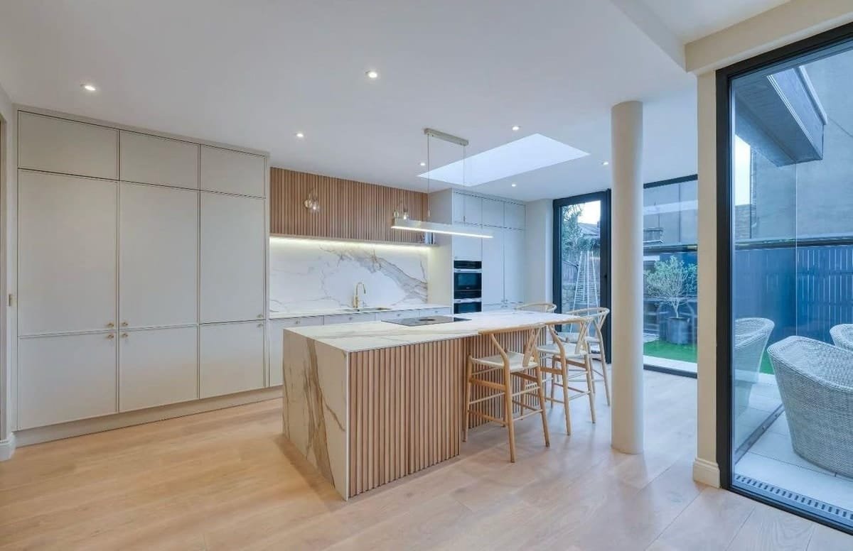 Modern kitchen with tall flat-panel cabinetry, a fluted island and a skylight