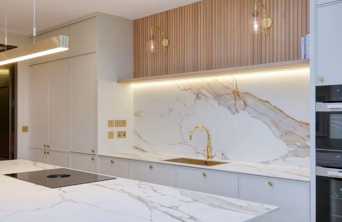 Marble-look backsplash with brass fixtures, a fluted wood shelf and integrated lighting