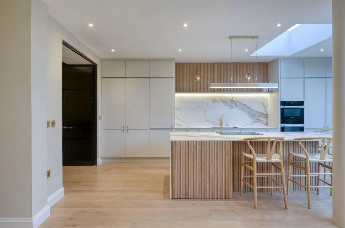 Open kitchen with a fluted wood island, tall cabinetry and a skylight