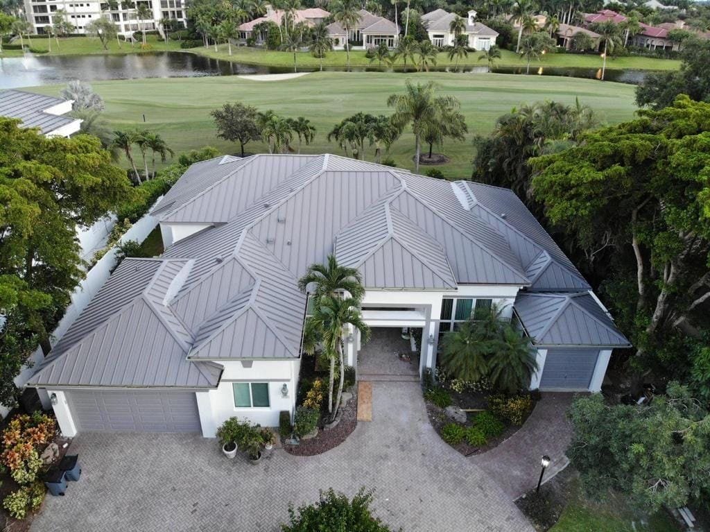 Aerial view of a home with a new standing-seam metal roof beside a golf course