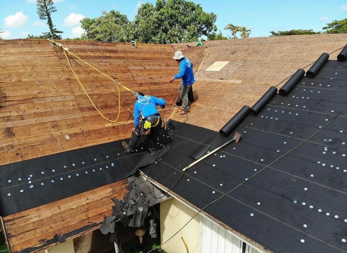 Roofers laying new underlayment over the roof decking