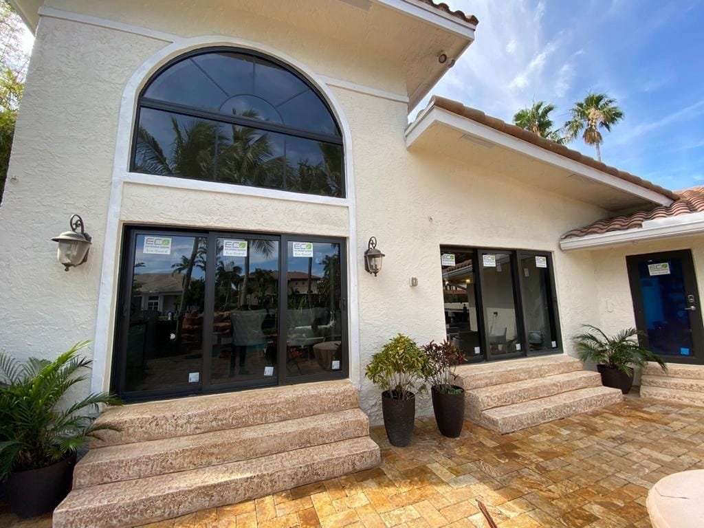 Stucco home with new dark-framed windows and doors under an arched window